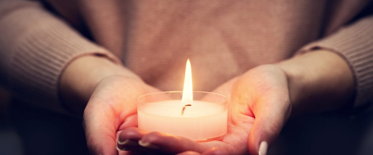 Candle light glowing in woman's hands. Praying, faith, religion concept.