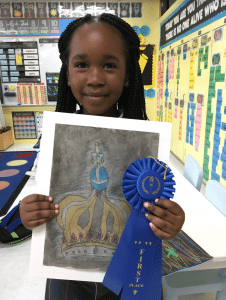 <em>Our Lady of Sorrows Catholic School 1st-grader Addison Jackson proudly displays her artwork of Our Lady of Fatima’s Crown and her blue ribbon for placing first in the Homewood Library’s Student Juried Art Contest.</em>