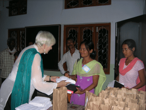 <em>Margaret O’Kelley distributes Assamese Bibles at a conference in India.</em>