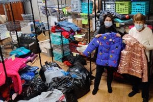 Ladies holding coats from the Prince of Peace Coat Drive