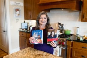 Danna holding cookbooks in kitchen