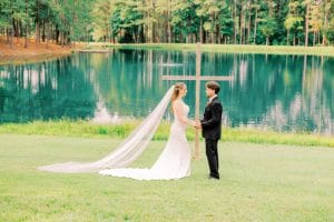 FoxHaven bride and groom in front of pond and cross FoxHaven bride and groom in front of pond and cross